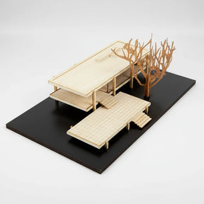 Wooden model of a house with a tree on a black platform
