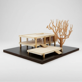 Model of a house with a tree on a black platform against a white background