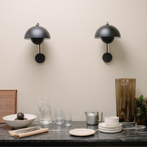 Black wall sconces on a neutral wall with a dining table setup featuring plates, glasses, and a teapot.