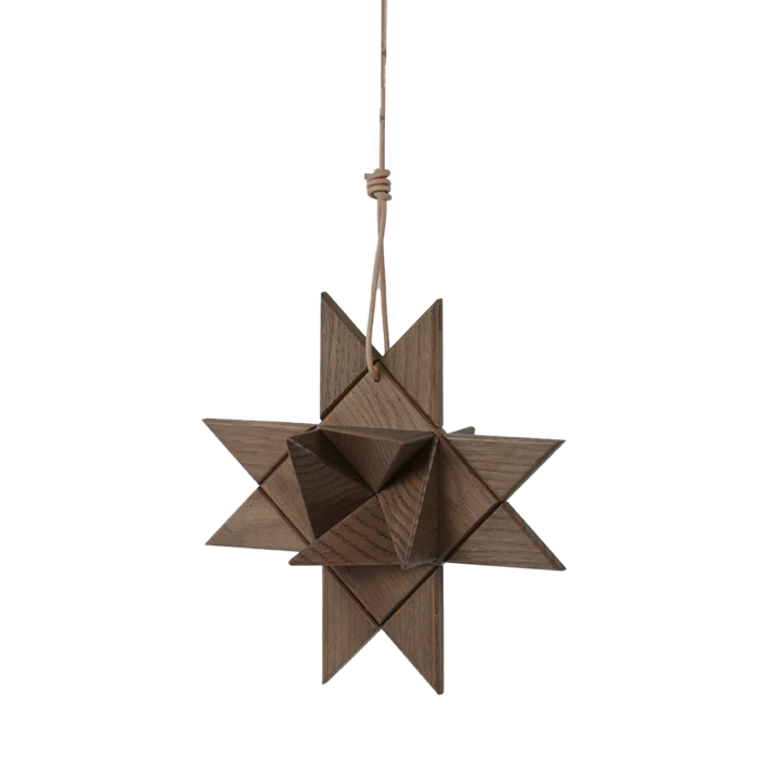 Hanging geometric star ornament crafted from smoked wood, composed of interlocking triangular facets and suspended by a natural cord, showcasing rich dark wood grain and a sculptural matte finish against a plain white background.