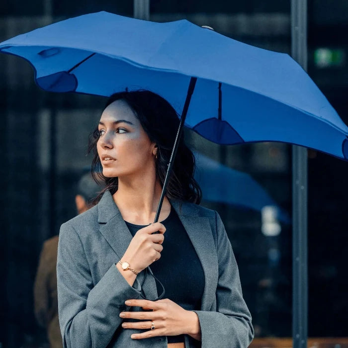 Woman holding a blue umbrella in an urban setting