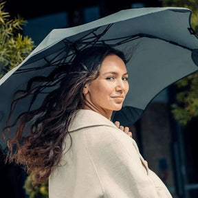 Woman holding a large umbrella outdoors with a blurred background