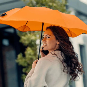 Woman holding an orange umbrella outdoors