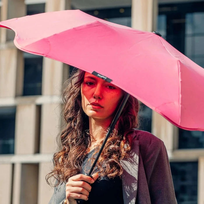 Woman holding a pink umbrella in front of a building