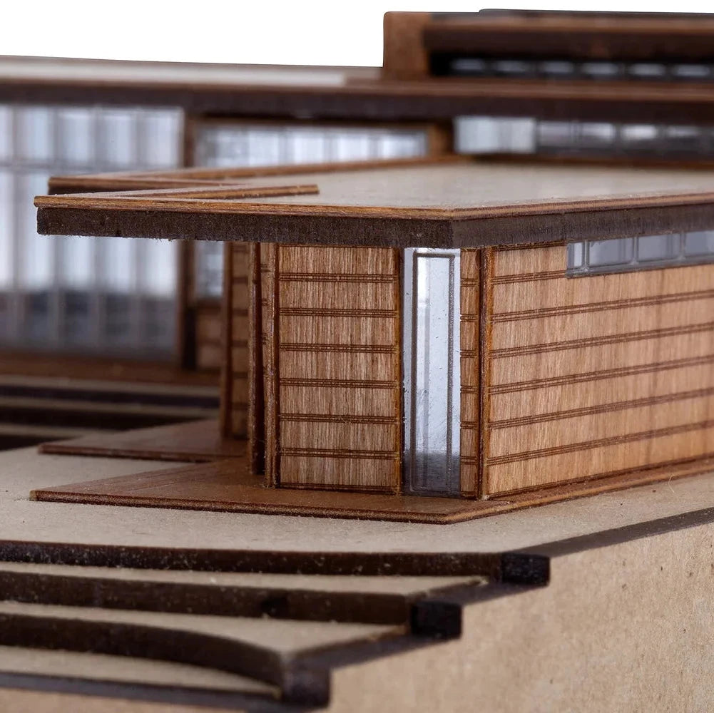 Model of a modern building with wooden exterior and glass windows on a neutral background