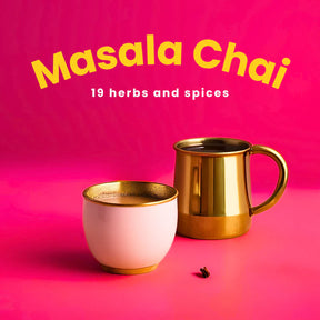 Two gold mugs with 'Masala Chai' text on a pink background