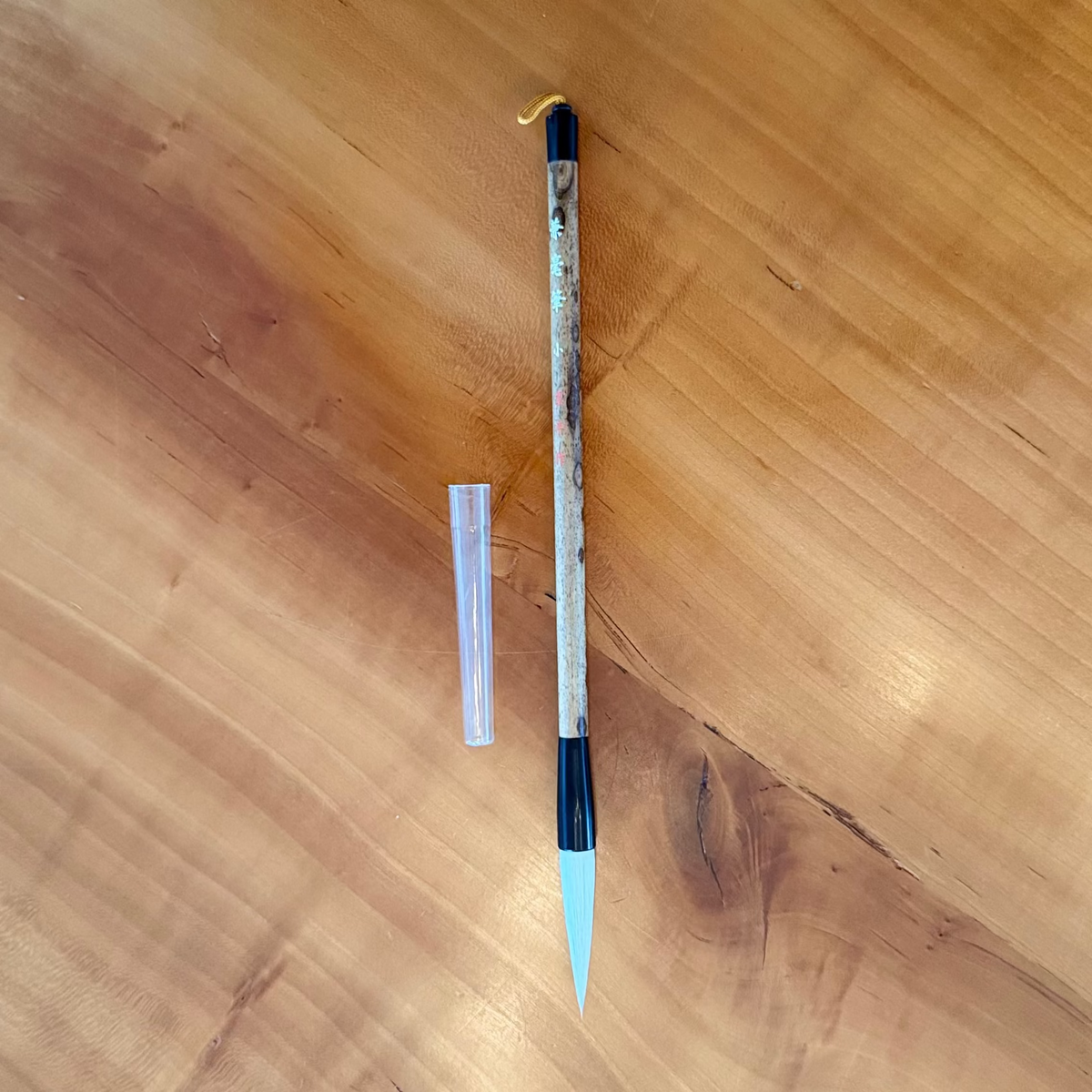 Long thin object with black and gold accents on a wooden surface