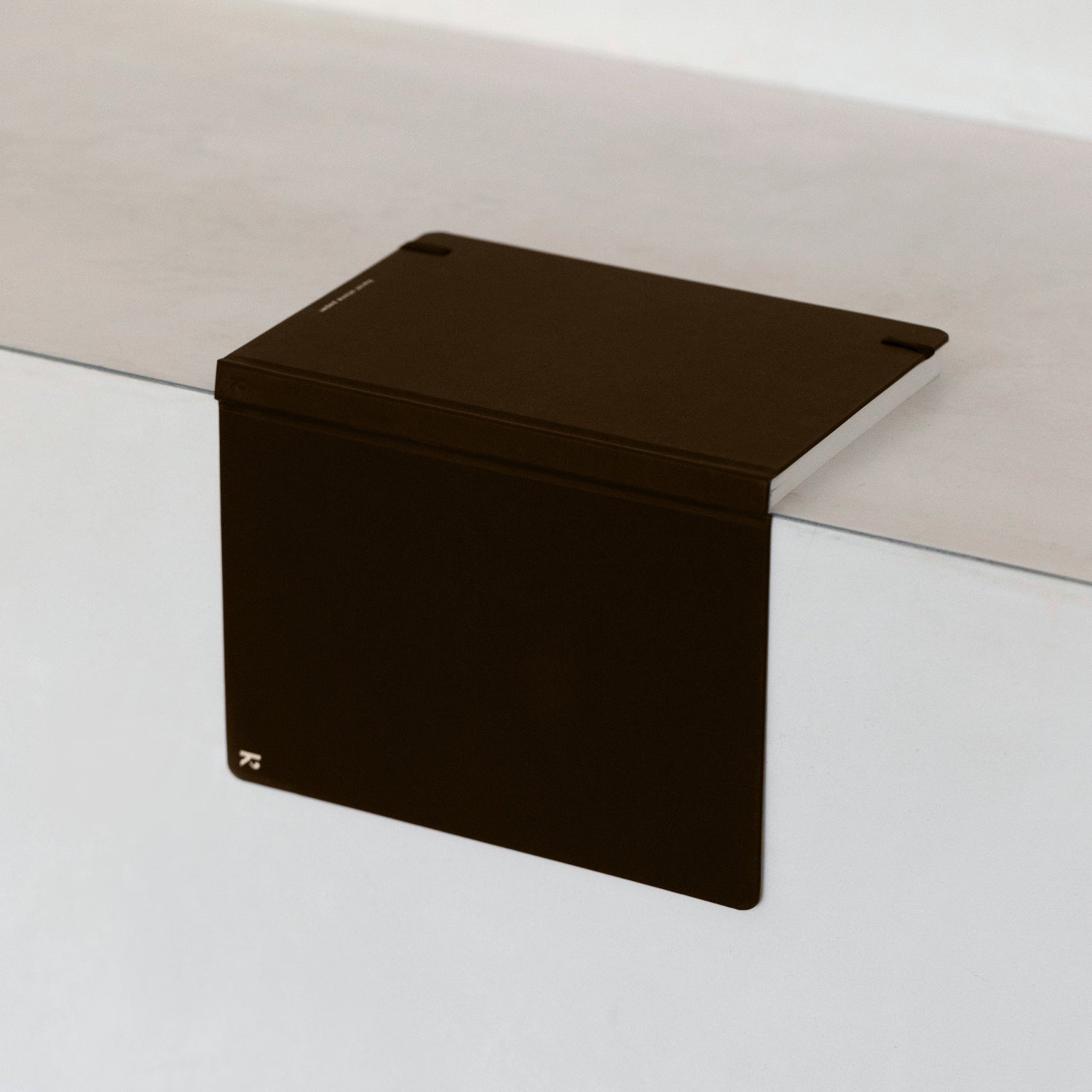 Black rectangular object on a white surface with a neutral background