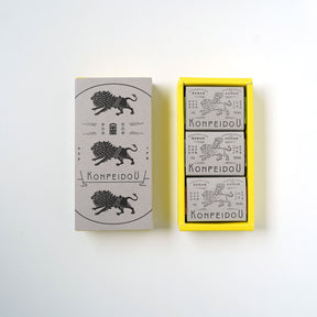 A set of three matchboxes from the brand KOMPEIDOU, displayed on a clean white background. The set includes one closed matchbox with a gray cover featuring a black illustration of a lion and the brand name, and an open yellow tray containing three individual matchboxes with gray covers.