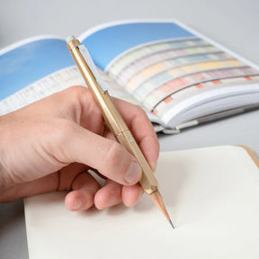 Hand holding a gold pen over a notebook with a colorful page.
