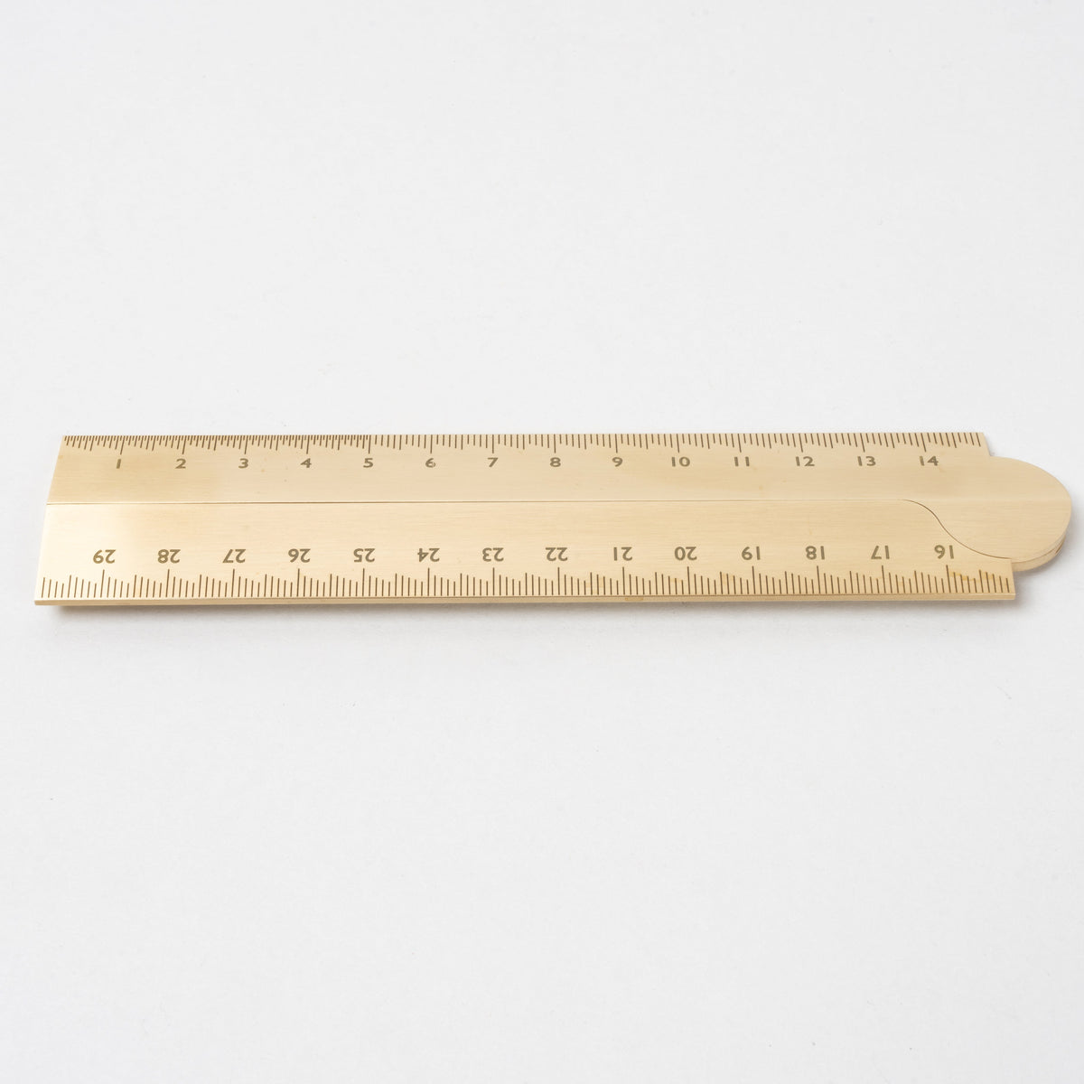 Minimalist brass ruler with engraved measurement markings, featuring a warm brushed metal finish, clean edges, and a smooth surface on a plain white background.