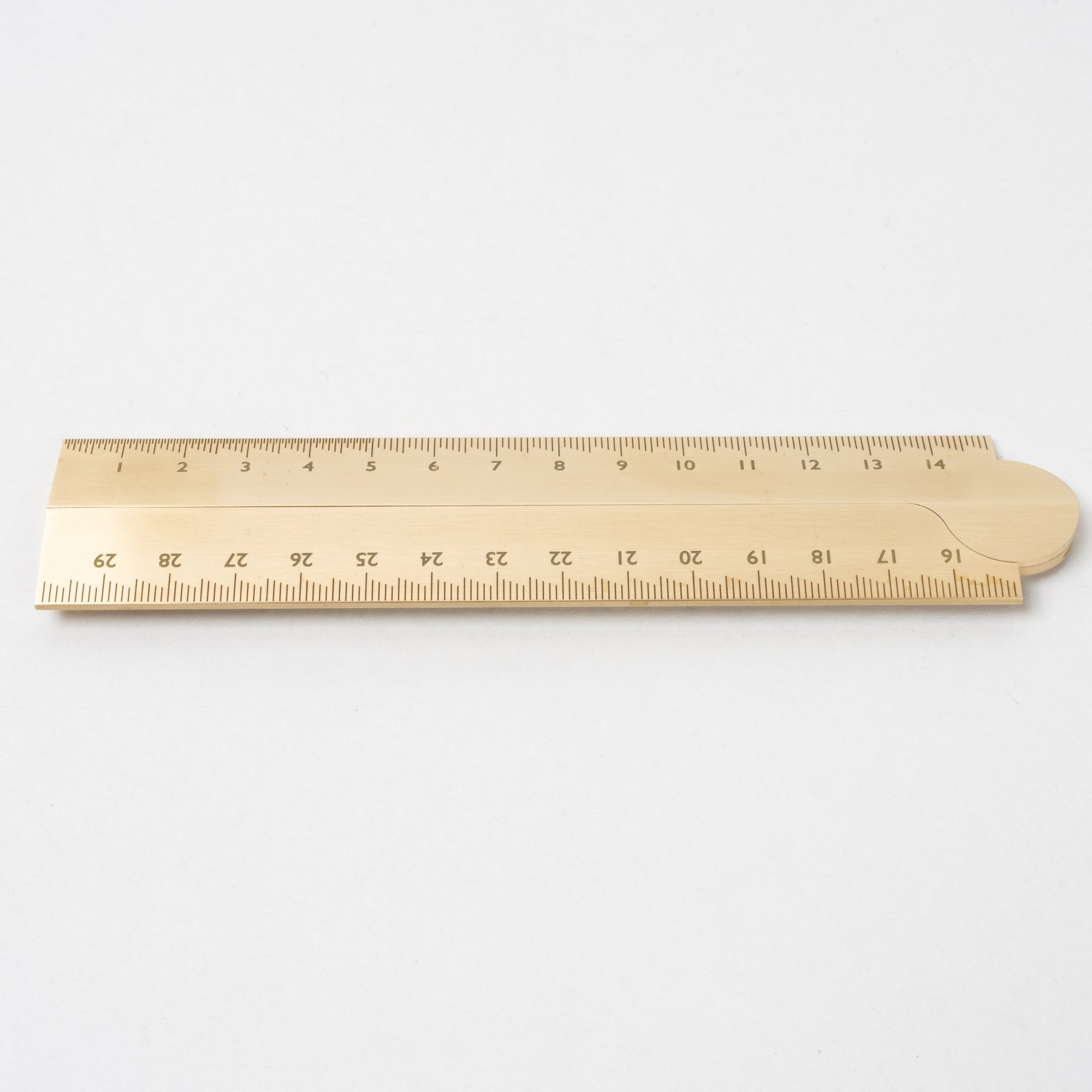 Minimalist brass ruler with engraved measurement markings, featuring a warm brushed metal finish, clean edges, and a smooth surface on a plain white background.