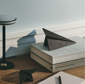 Stack of books titled 'The Design Hotels' with a geometric wooden object on top, placed on a wooden surface.
