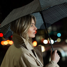 Woman holding an umbrella in a city street at night with blurred lights in the background