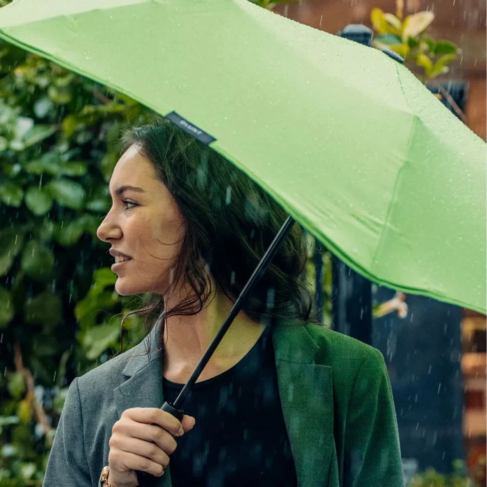 Woman holding a green umbrella in the rain with blurred background