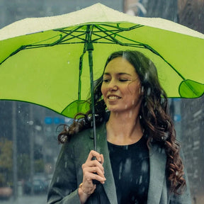 Woman holding a green umbrella in the rain