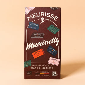Front view of Meurisse Meurissette dark chocolate packaging, featuring illustrated mini chocolate tablets in assorted flavors on a deep brown box, labeled ‘10 mini tablets,’ made in Belgium.
