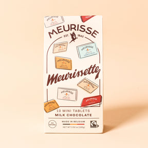 Front view of Meurisse Meurissette milk chocolate packaging, a cream-colored box illustrated with assorted mini chocolate tablets, labeled ‘10 mini tablets,’ made in Belgium.