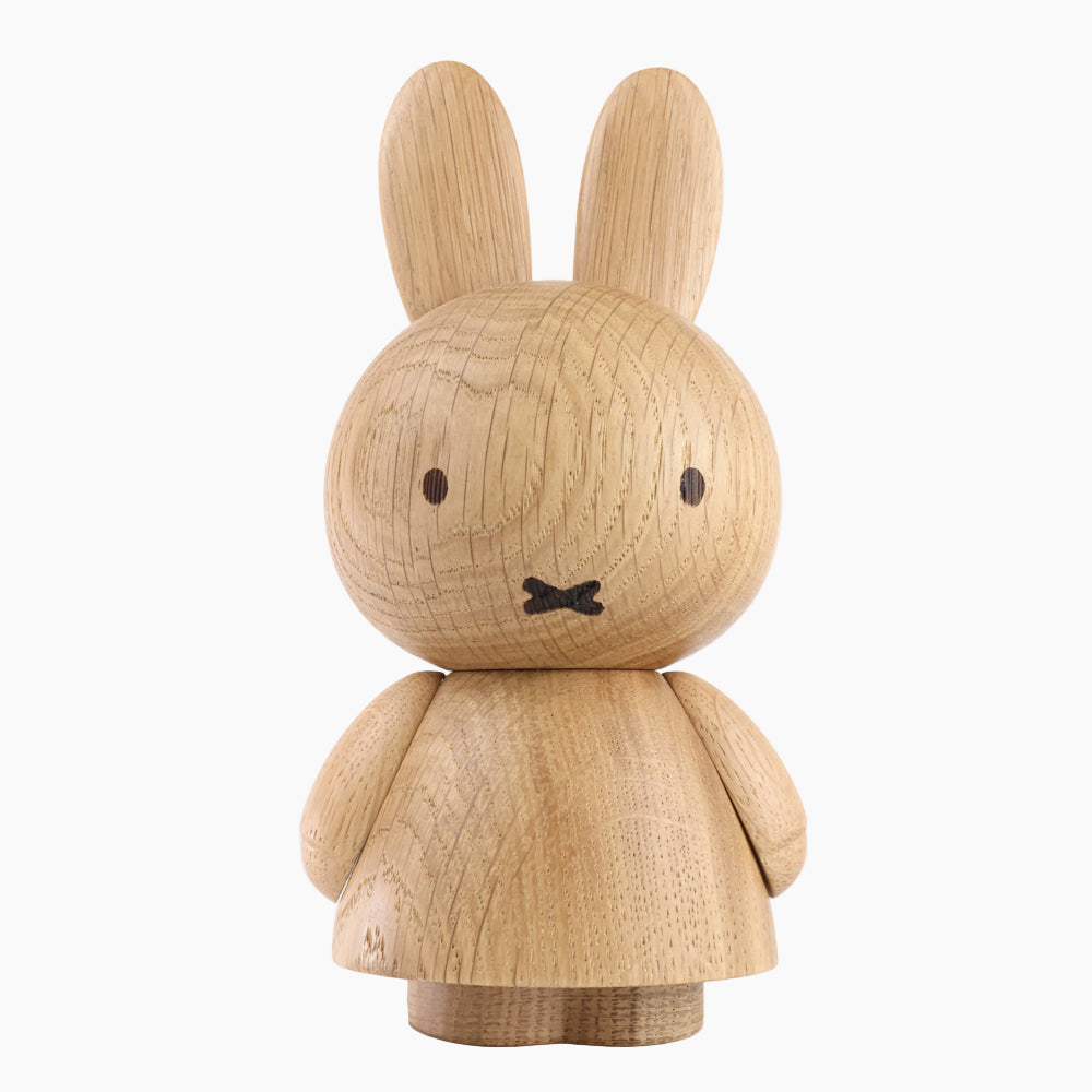 Front view of a wooden figurine of an animated cartoon character carved from light oak, featuring long upright ears, simple facial details, a rounded sculpted body with small arms, visible natural wood grain, and a matte surface on a plain white background.