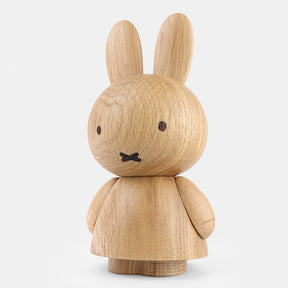 Wooden figurine of an animated cartoon character carved from light oak, featuring long upright ears, simple facial details, a rounded sculpted body with small arms, visible natural wood grain, and a matte surface on a plain white background.