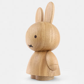Wooden figurine of an animated cartoon character carved from light oak, featuring long upright ears, simple facial details, a rounded sculpted body with small arms, visible natural wood grain, and a matte surface on a plain white background.