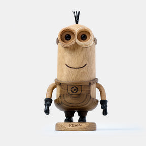 Wooden figurine of an animated cartoon character carved from light and dark wood, featuring a tall cylindrical body, round goggle-style eyes, a carved smiling mouth, engraved clothing details, small sculpted arms with dark gloves, visible natural wood grain, and a matte surface on a plain white background.