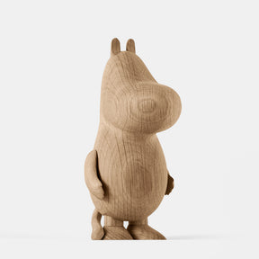 Wooden figurine of an animated cartoon character carved from light oak, featuring a rounded elongated head with small ear details, a smooth sculpted body, simplified limbs, visible natural wood grain, and a matte surface on a plain white background