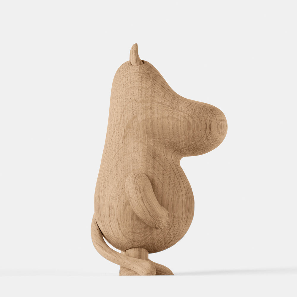 Wooden figurine of an animated cartoon character carved from light oak, featuring an elongated rounded head with small ear detail, a smooth sculpted body, simplified limbs and tail, visible natural wood grain, and a matte surface on a plain white background.