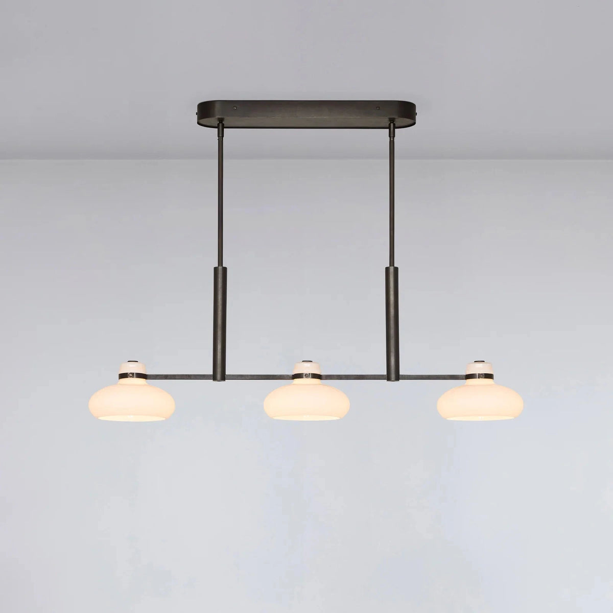 Modern pendant light with three bulbs on a plain background