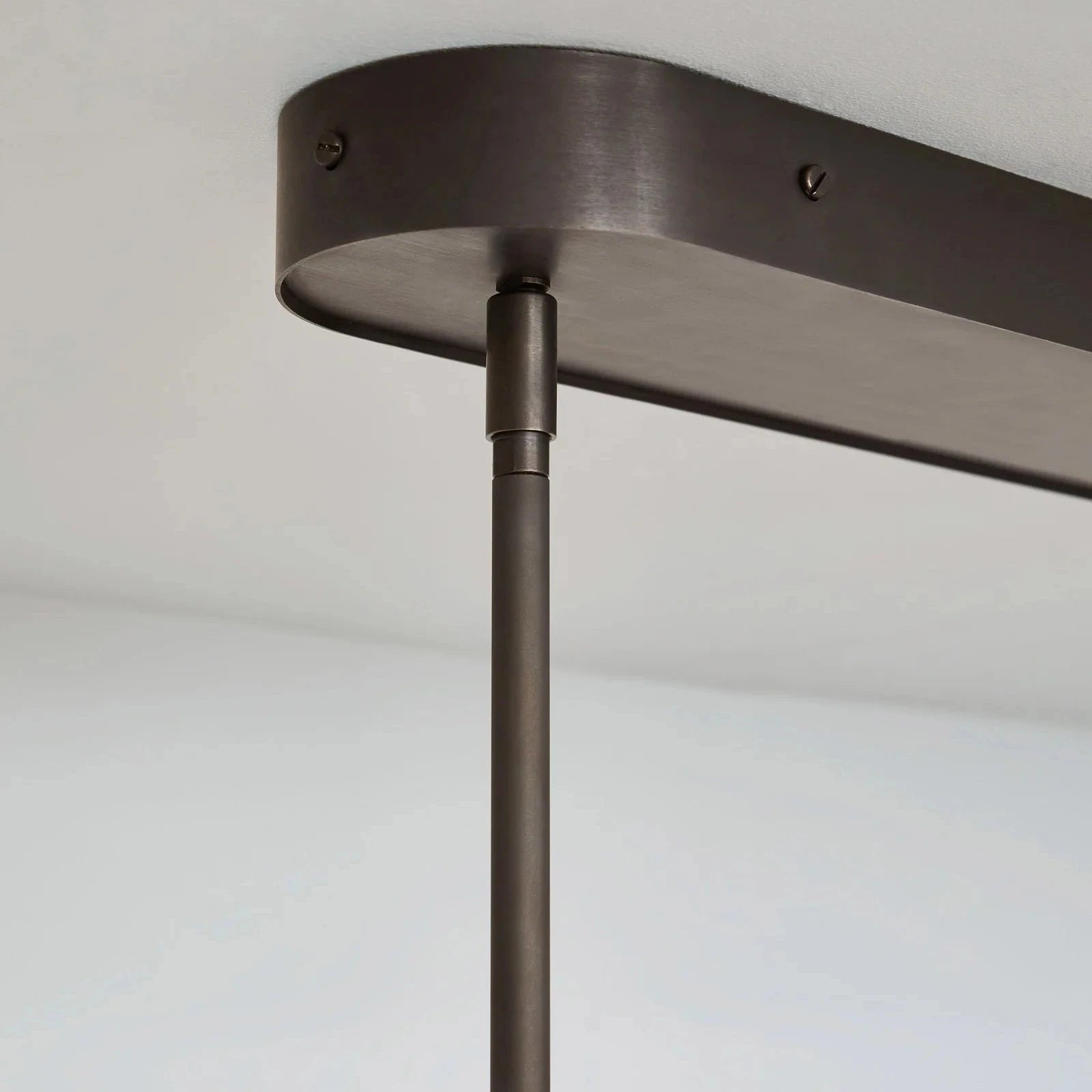 Close-up of a dark metal pendant light fixture against a plain background