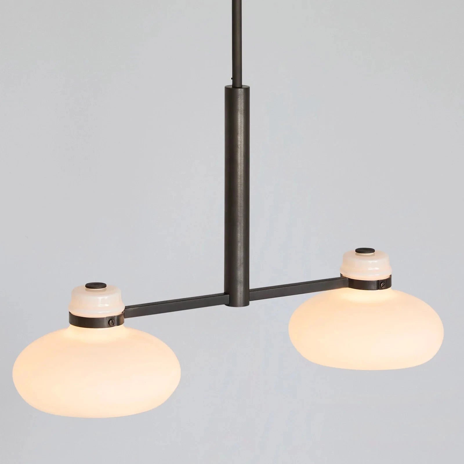 Modern pendant light with two round glass shades on a gray background