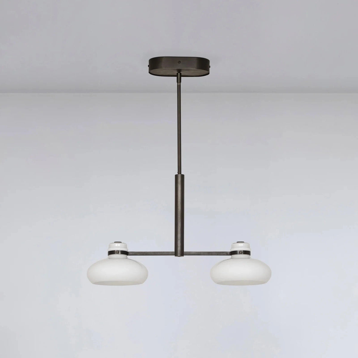 Modern pendant light with two round glass shades on a plain background