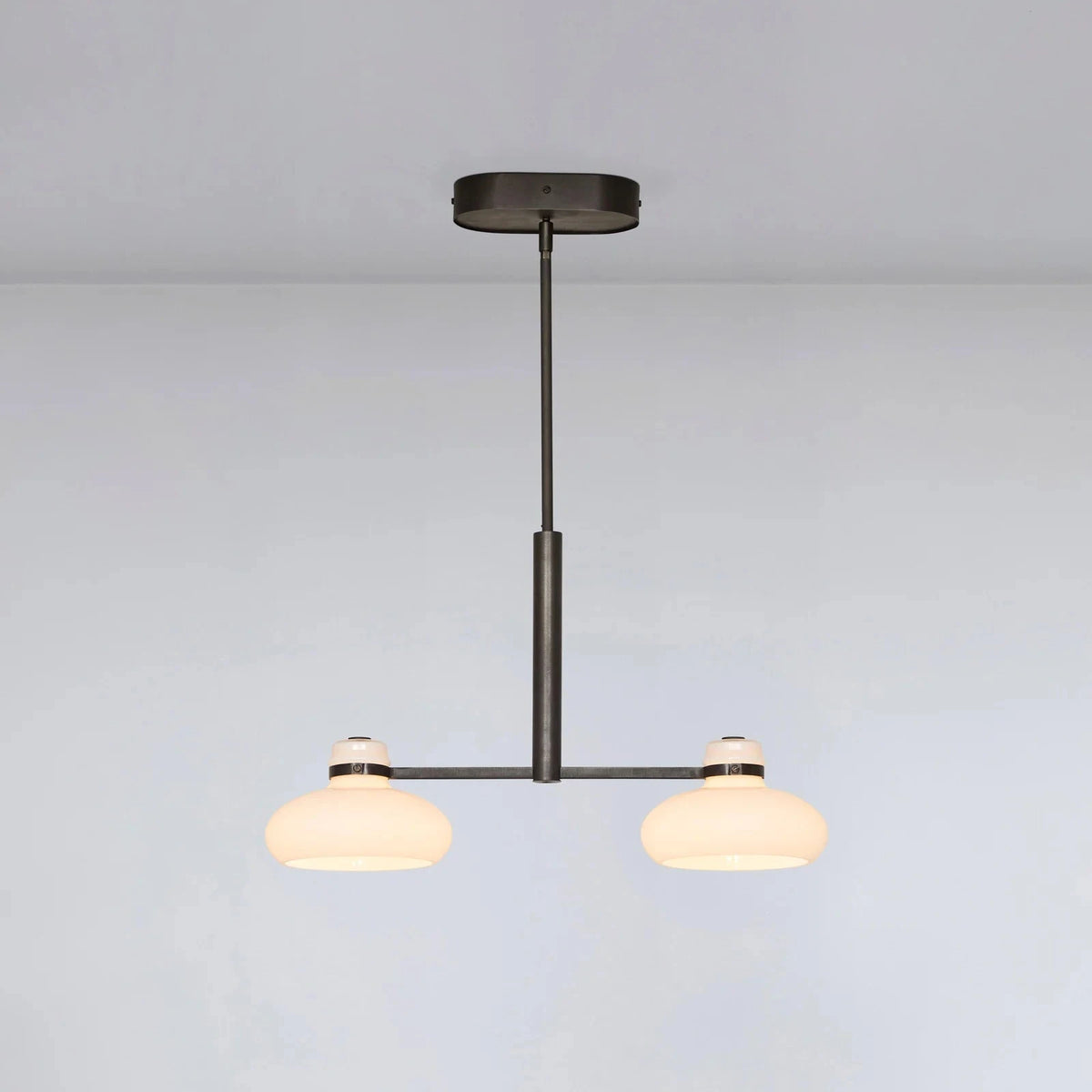 Modern pendant light with two glass shades on a plain background