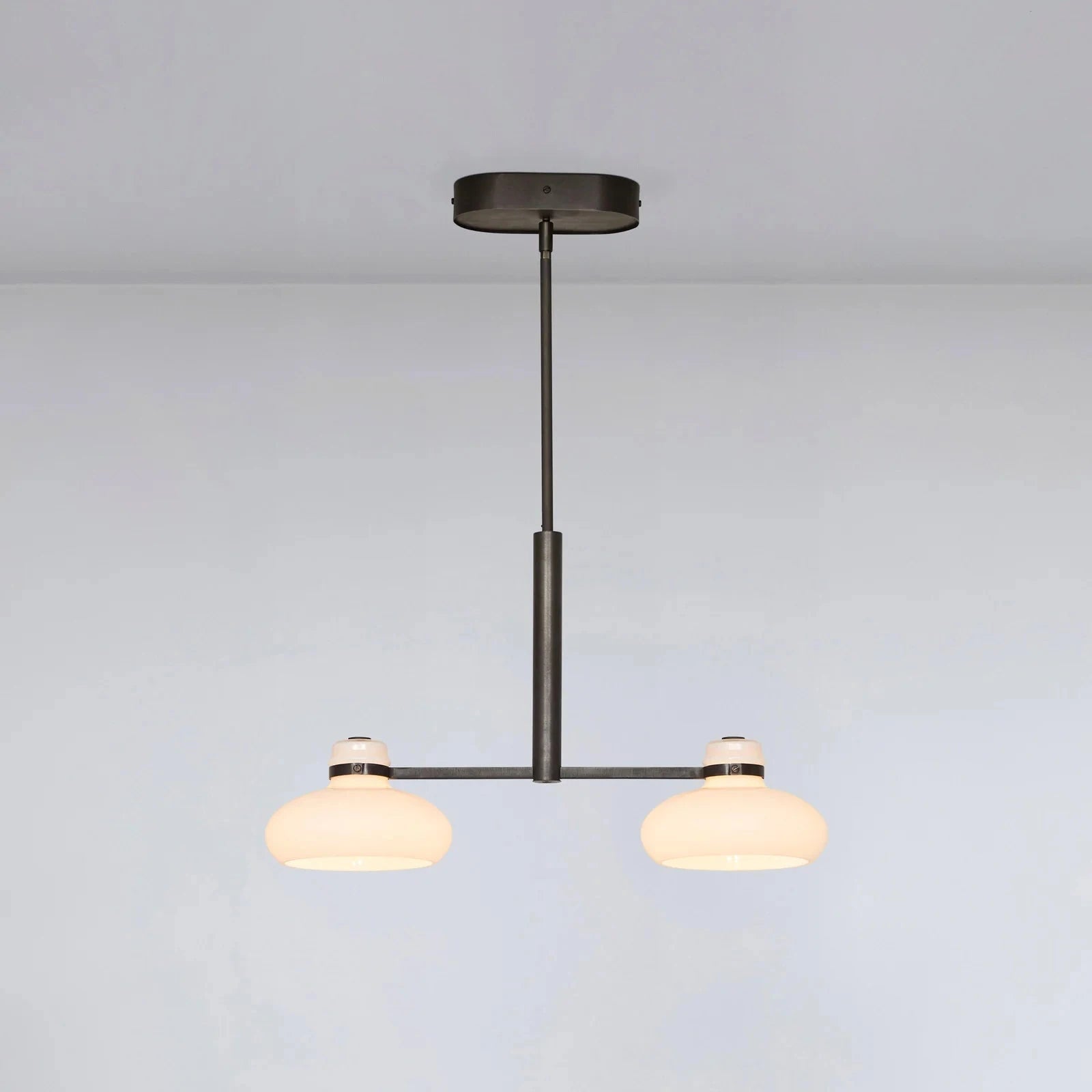 Modern pendant light with two glass shades on a plain background