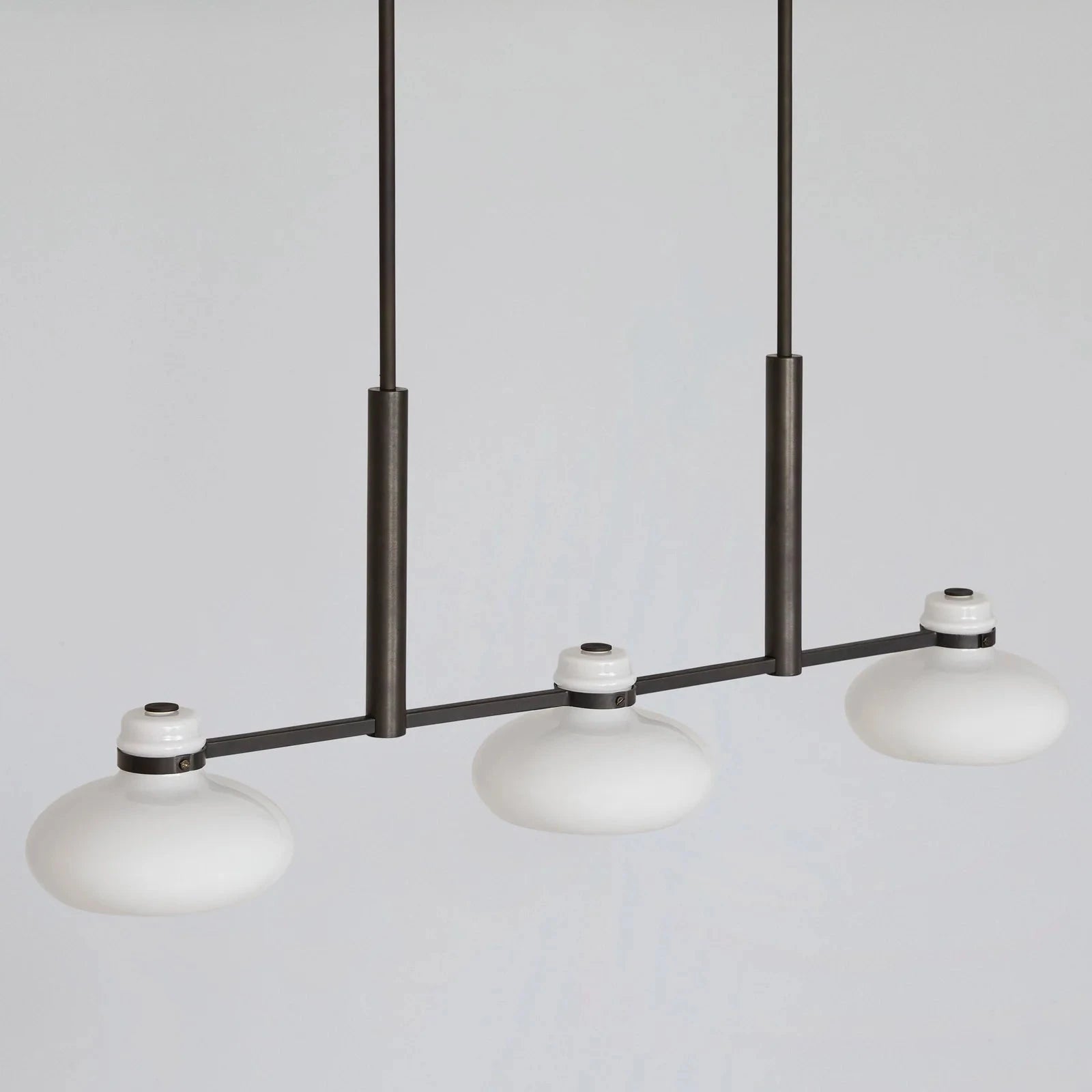 Modern pendant light with three white glass shades on a gray background