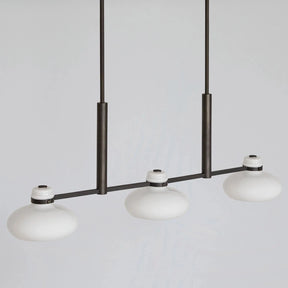 Modern pendant light with three white glass shades on a gray background