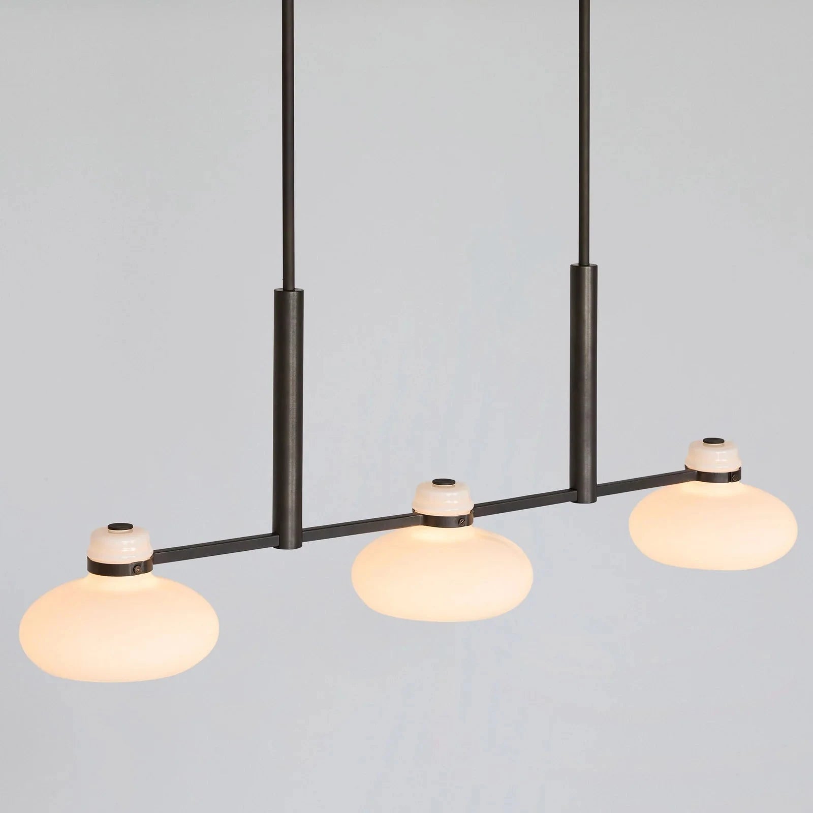 Modern pendant light with three glass bulbs on a plain background