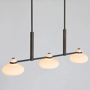 Modern pendant light with three glass bulbs on a plain background