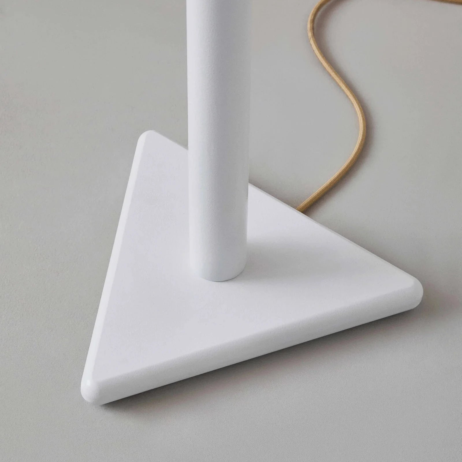White lamp with a triangular base on a gray surface