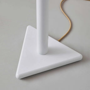 White lamp with a triangular base on a gray surface