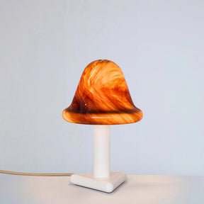 Mushroom-shaped lamp with orange and brown marbled design on a white base against a light gray background