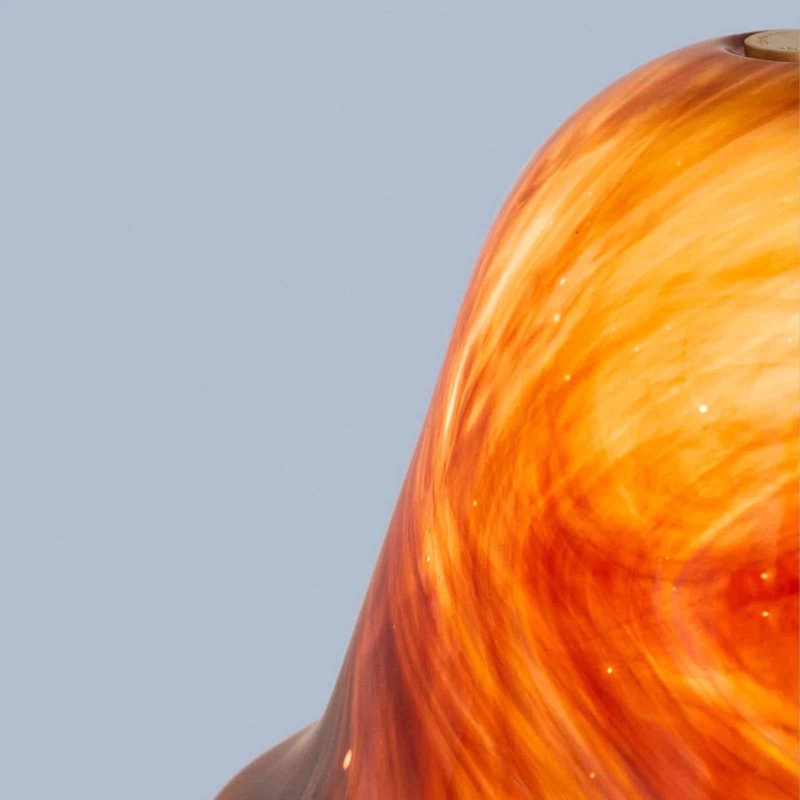 Close-up of a swirling orange and red glass object on a gray background