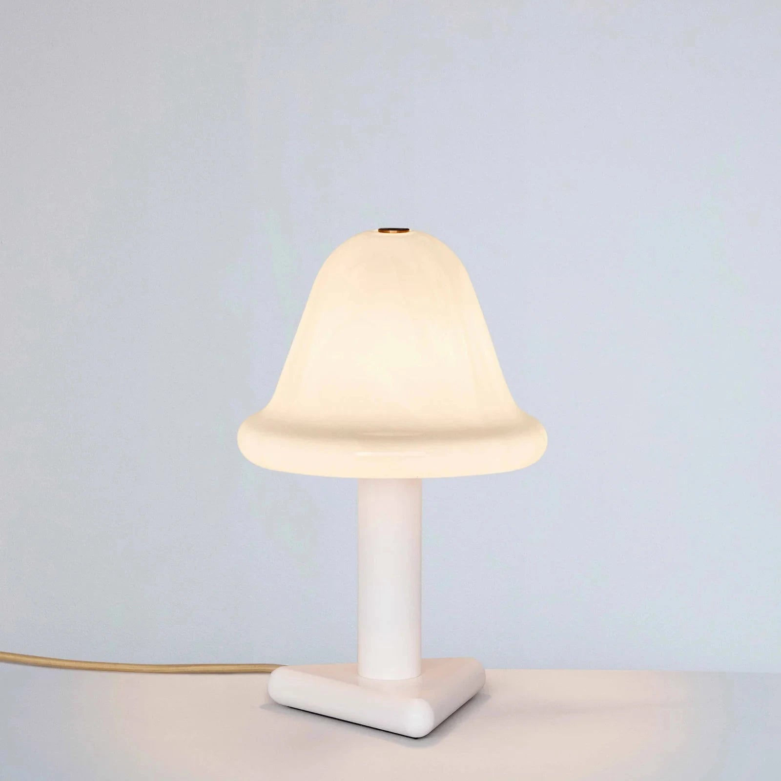 Small table lamp with a white base and shade on a light gray background