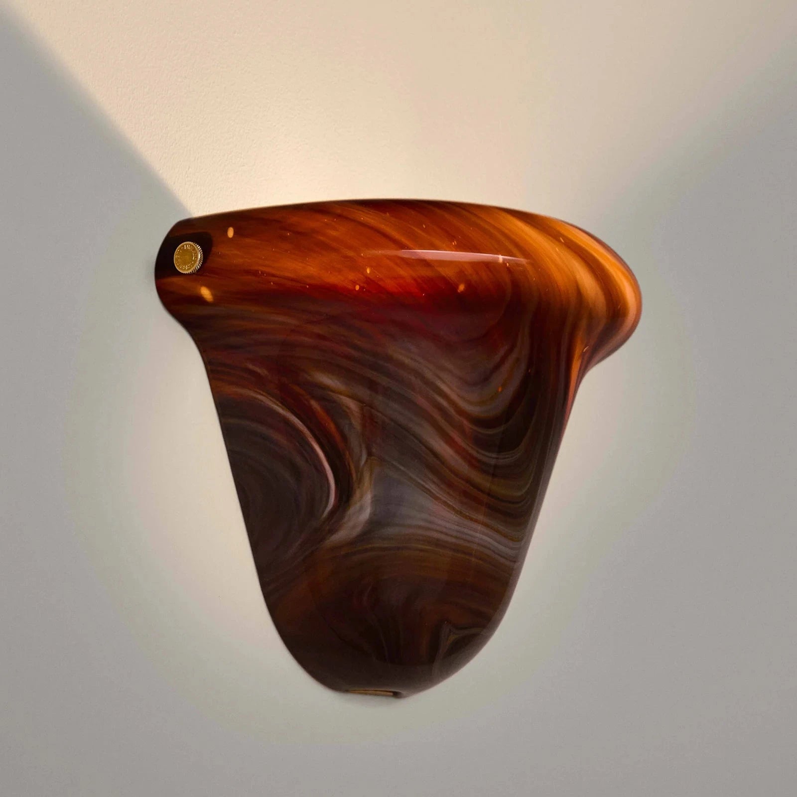 Decorative wall sconce with brown and red marbled design on a gray background