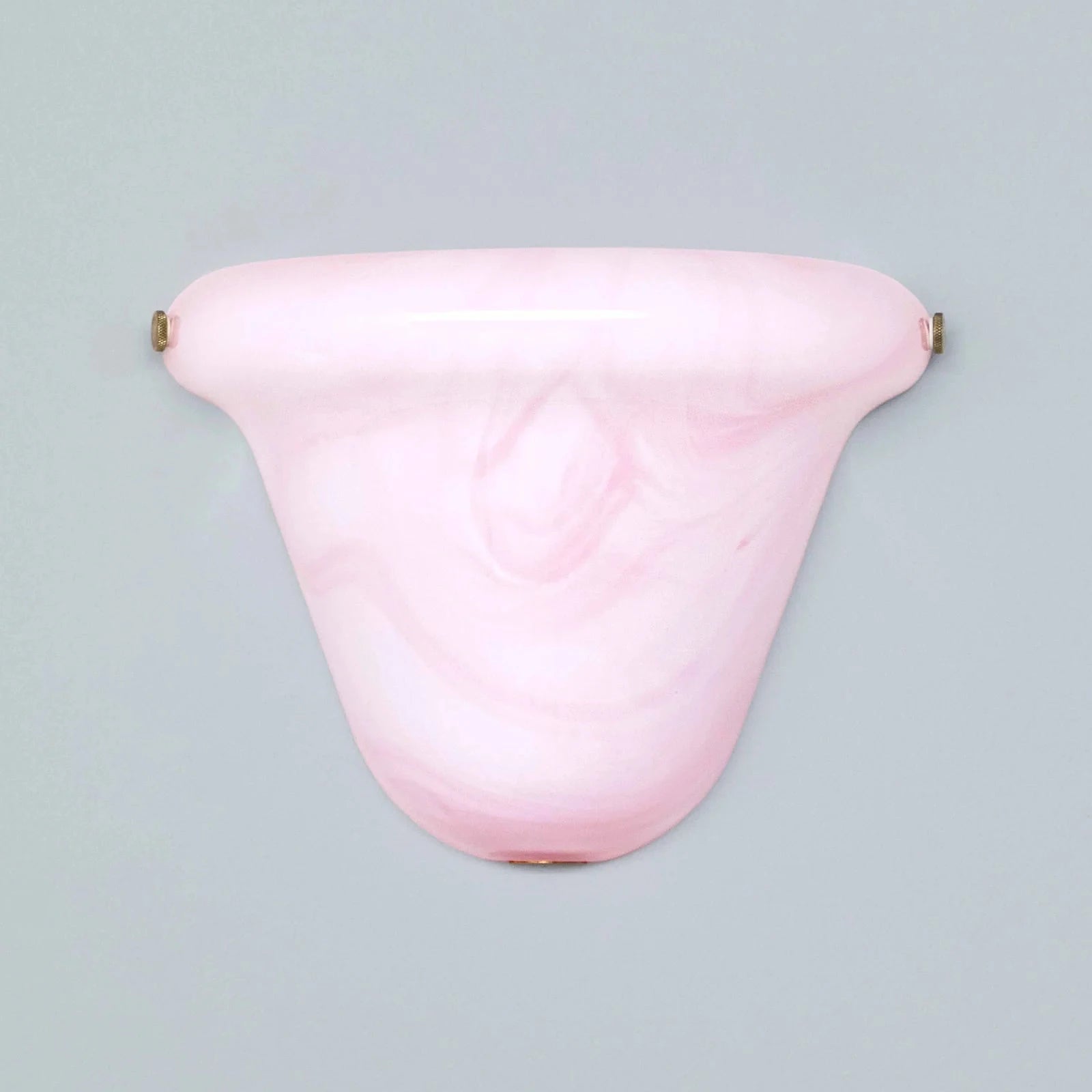 A light pink marbled glass wall sconce with small brass-colored mounting hardware on either side, shown against a solid light gray background.
