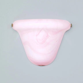 A light pink marbled glass wall sconce with small brass-colored mounting hardware on either side, shown against a solid light gray background.