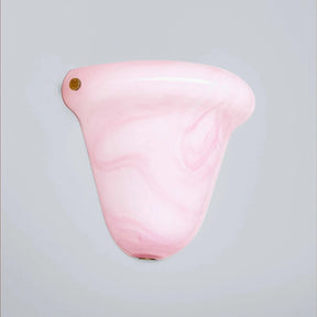 A light pink translucent plastic cup with a marbled swirl pattern and a small gold screw-on cap, shown against a solid light gray background.