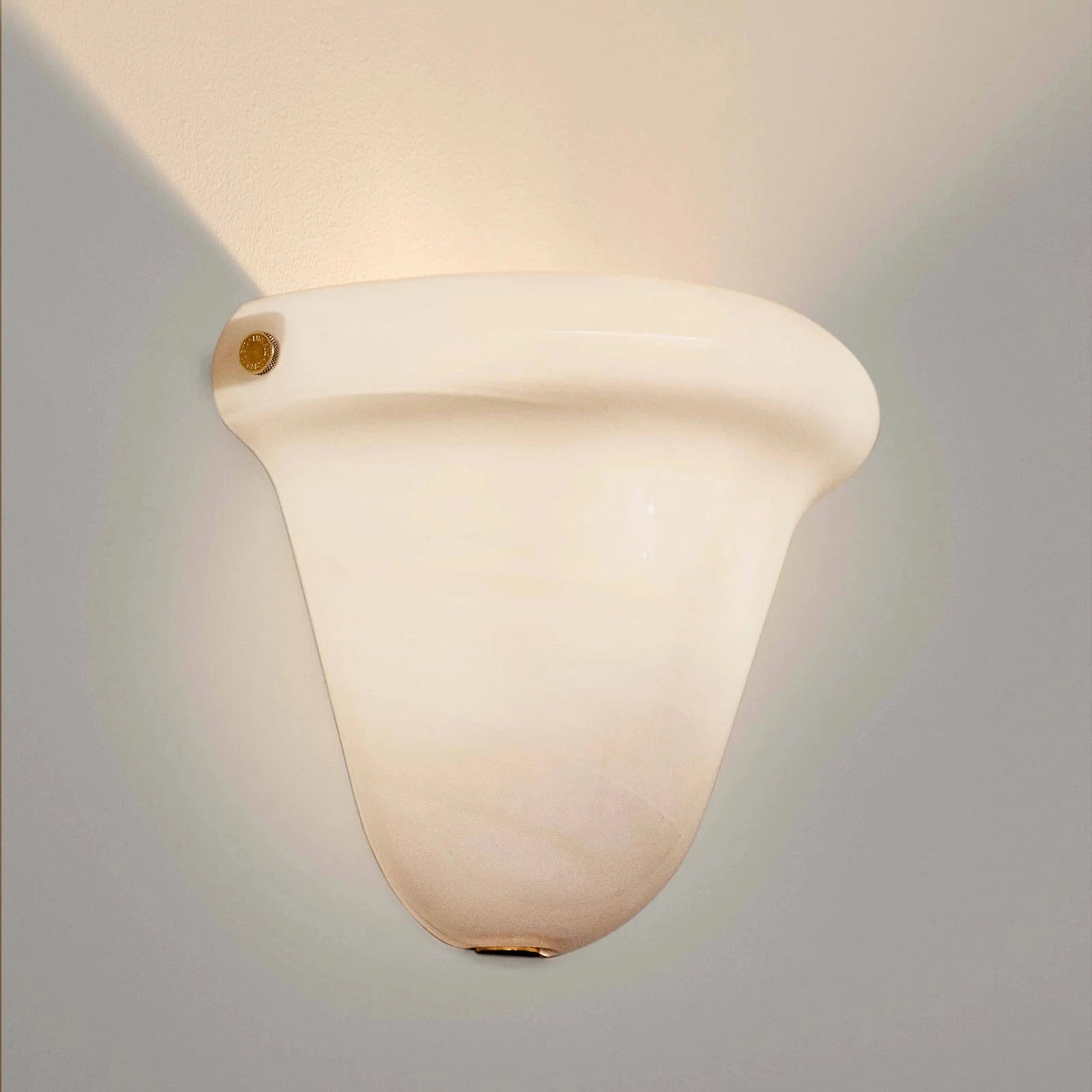 A modern wall-mounted sconce with a curved, bell-shaped frosted glass shade, shown illuminated against a neutral gray background.