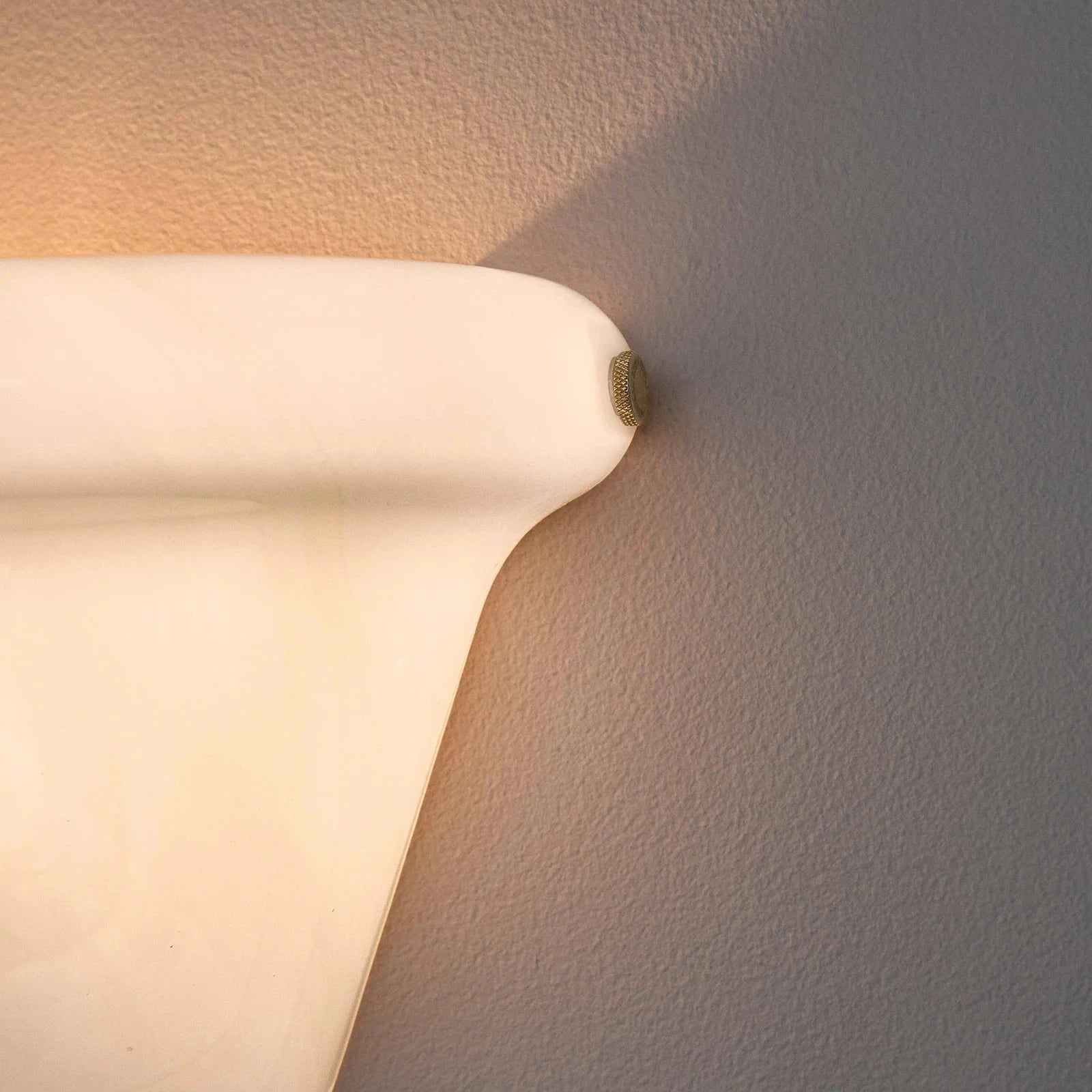 Wall-mounted light fixture casting a warm glow on a textured wall.