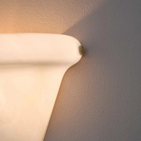 Wall-mounted light fixture casting a warm glow on a textured wall.